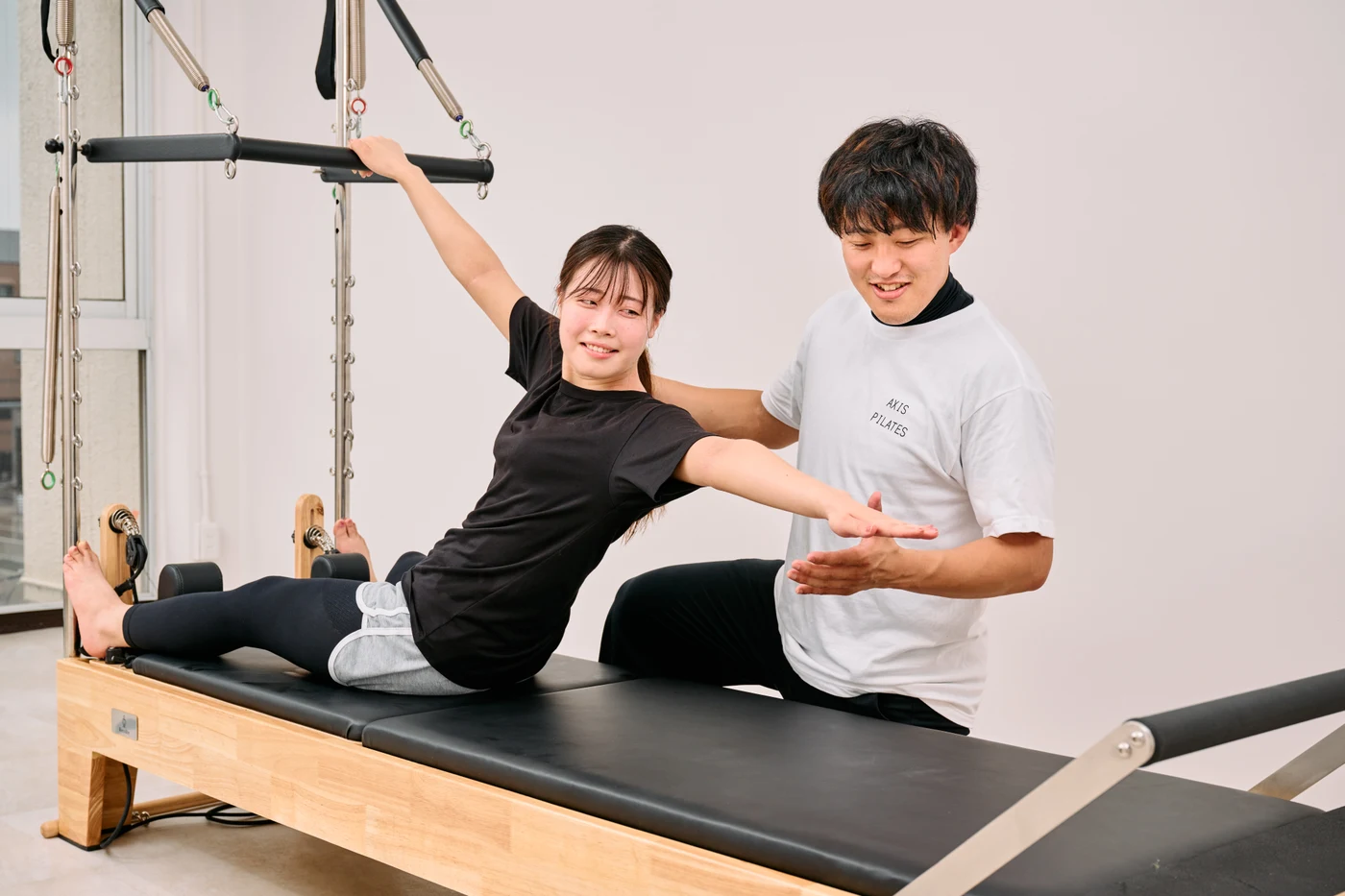 マシンを使用しトレーナーと行うピラティス
